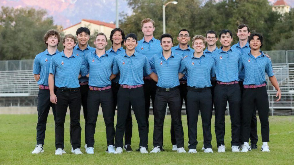 The men's golf team stand for a group picture on a field. They wear light blue shirts with a small Cecil Sagehen logo on the upper left and black pants for their uniform.